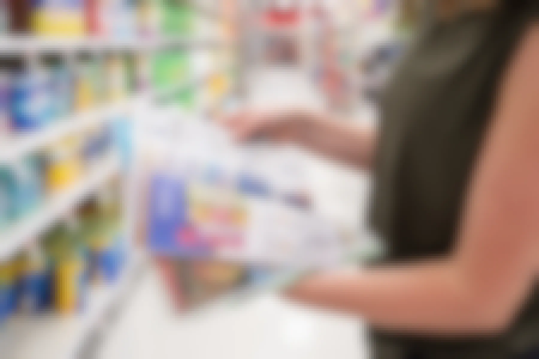 A woman flipping through newspaper coupons in a grocery store aisle 