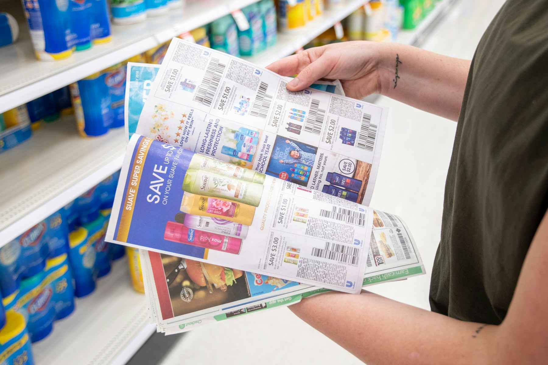 Woman flipping through manufacturer coupons in a coupon insert at store.