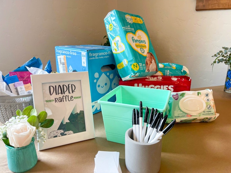 Packages of diapers and baby wipes on a table next to a sign that says "Diaper Raffle".