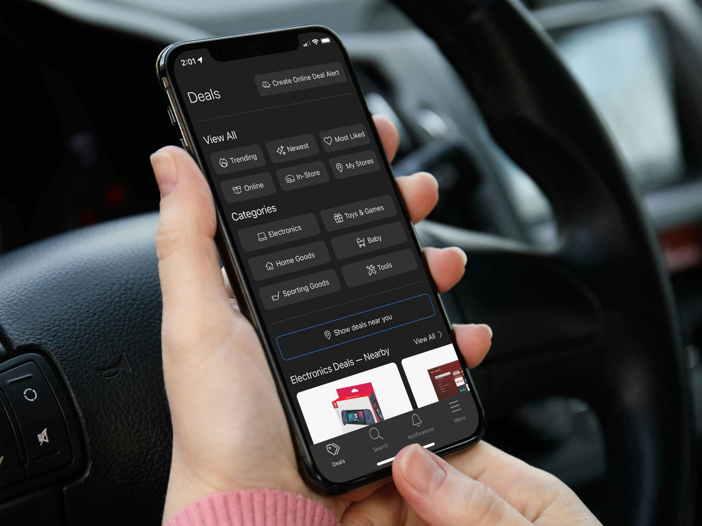 A person sitting in their car, using a phone displaying the Brickseek app.