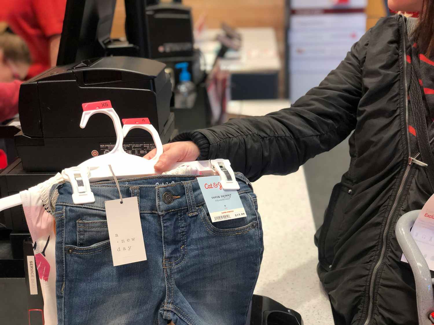 Person holding a couple pairs of Cat and Jack jeans over the Target return counter