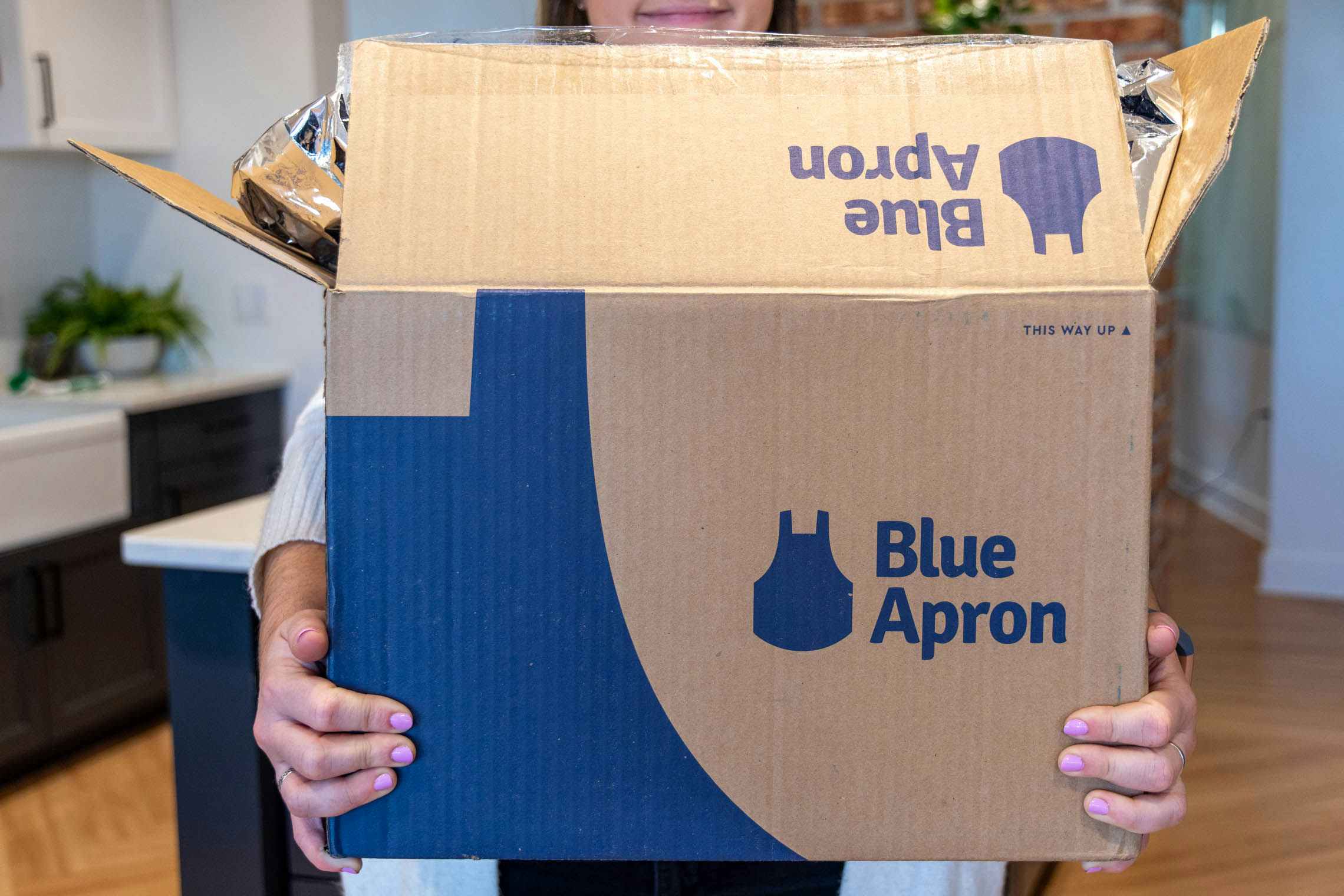 Someone holding a blue apron meal kit box.