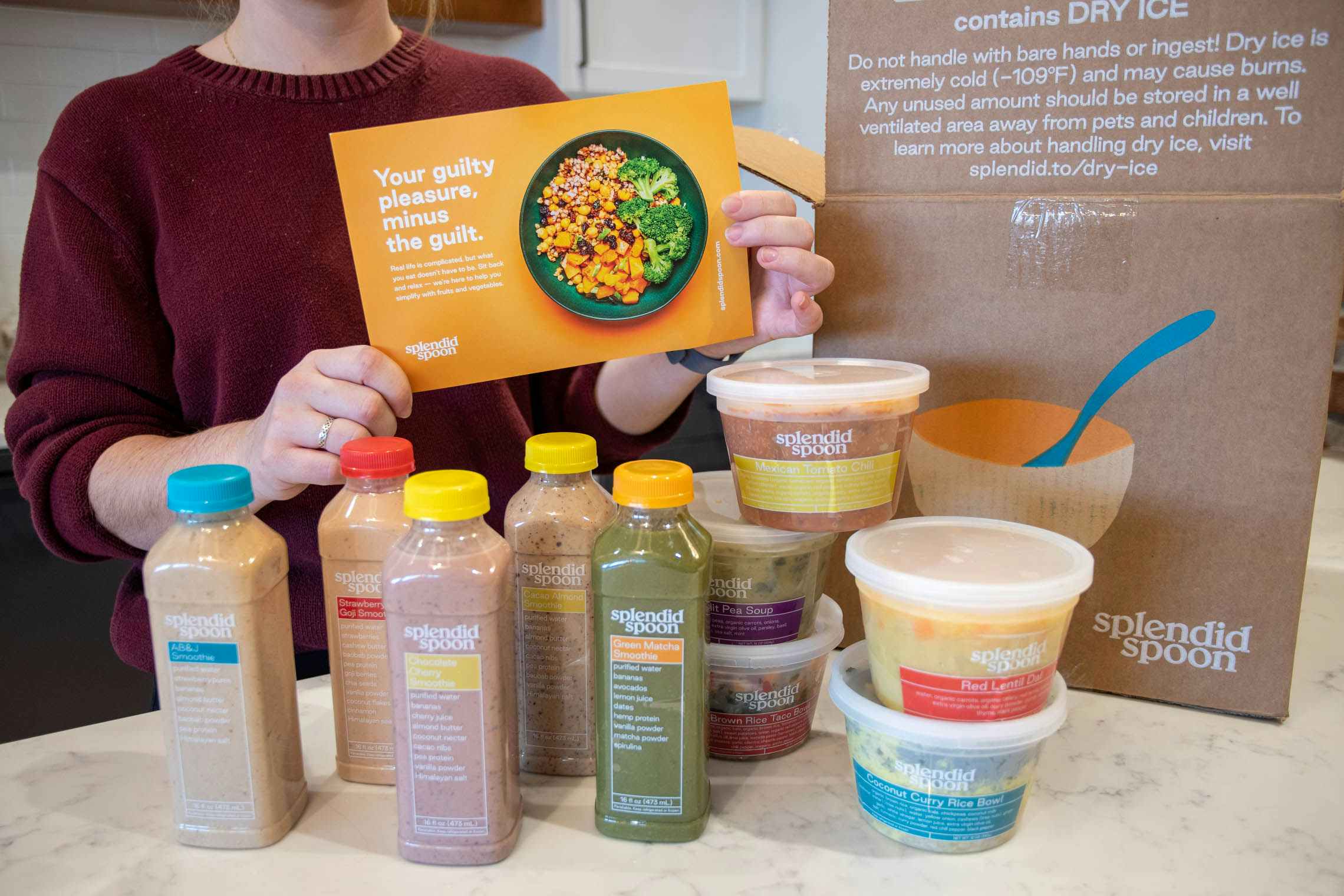 A woman unpacking the shakes and meal bowls from a Splendid Spoon meal kit box.