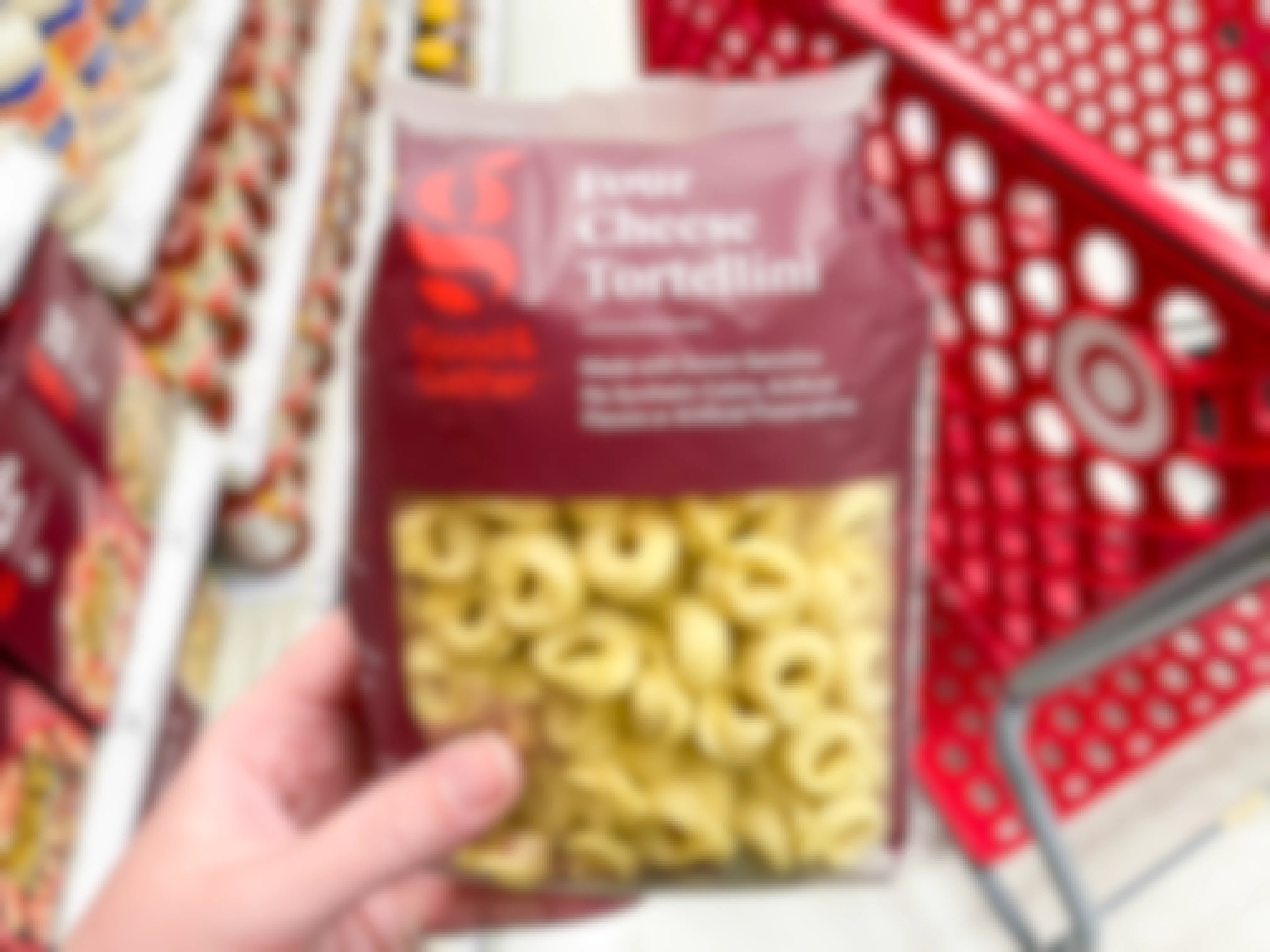 A person holding a package of Good and Gather tortellini, on the pasta aisle inside Target