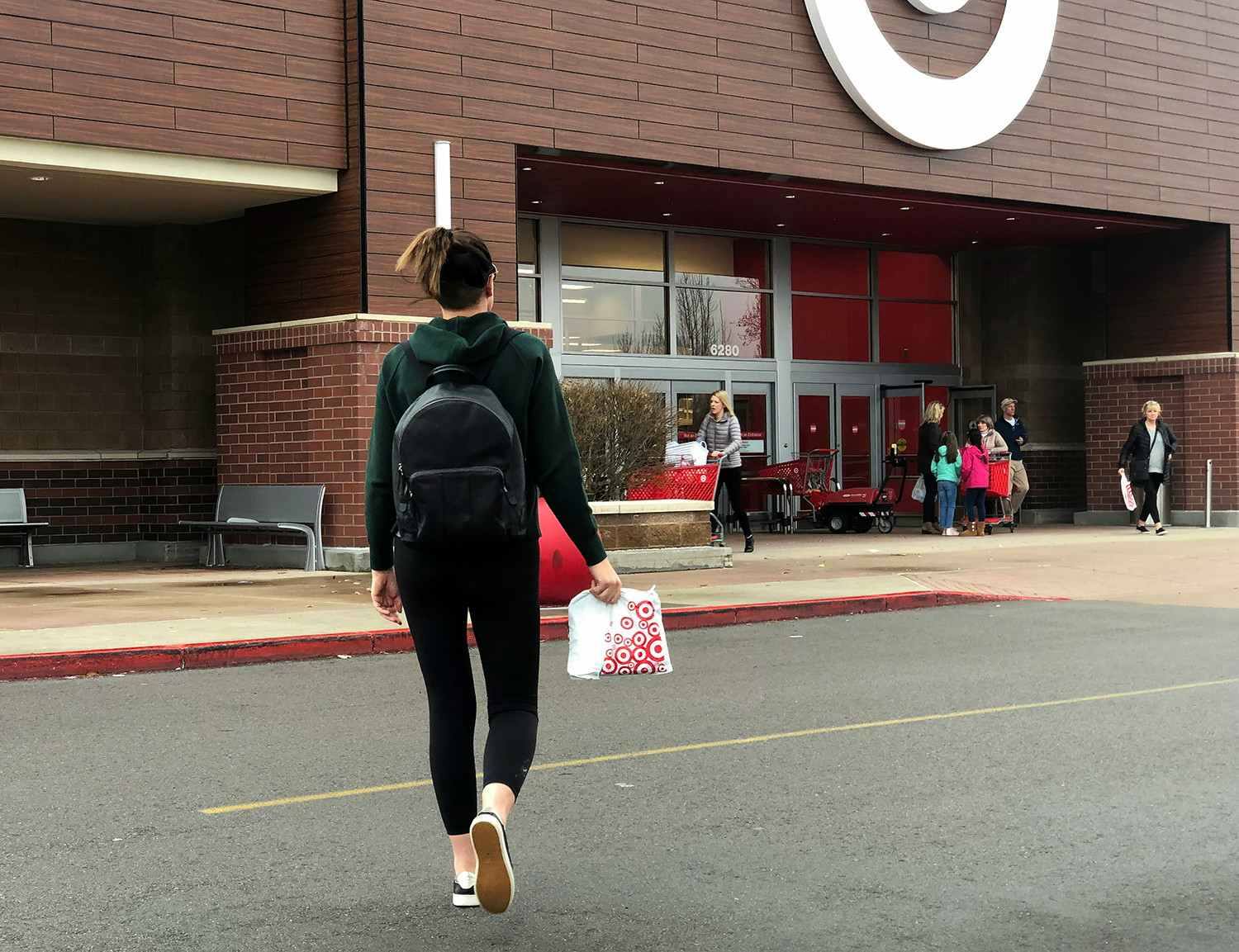 A person carrying a target bag walking toward the Target entrance.