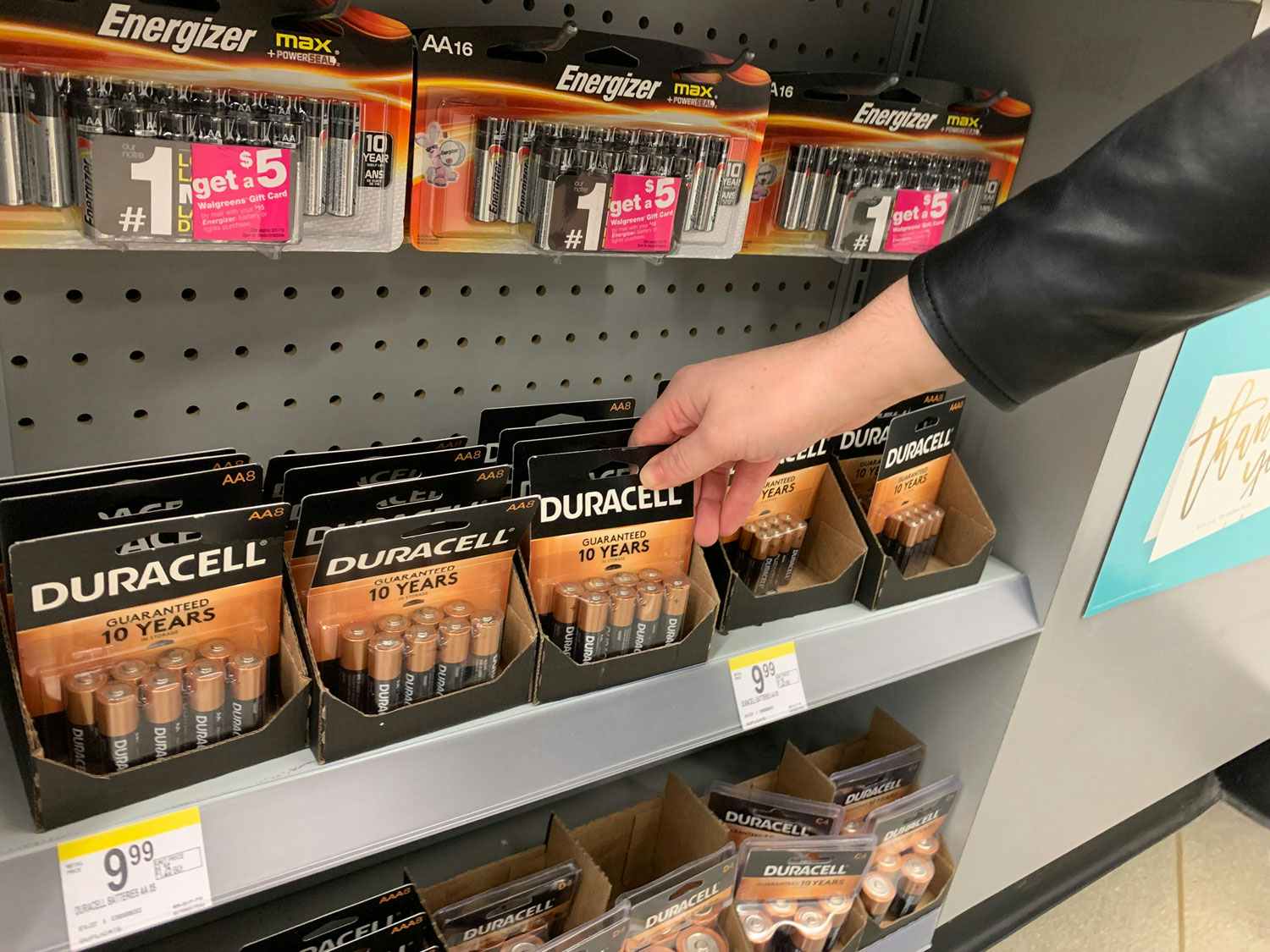 A person taking batteries off a shelf