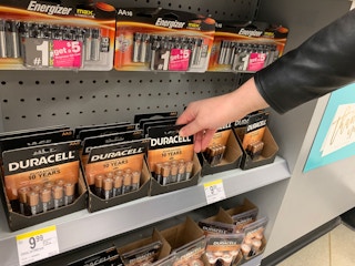 A person taking batteries off a shelf