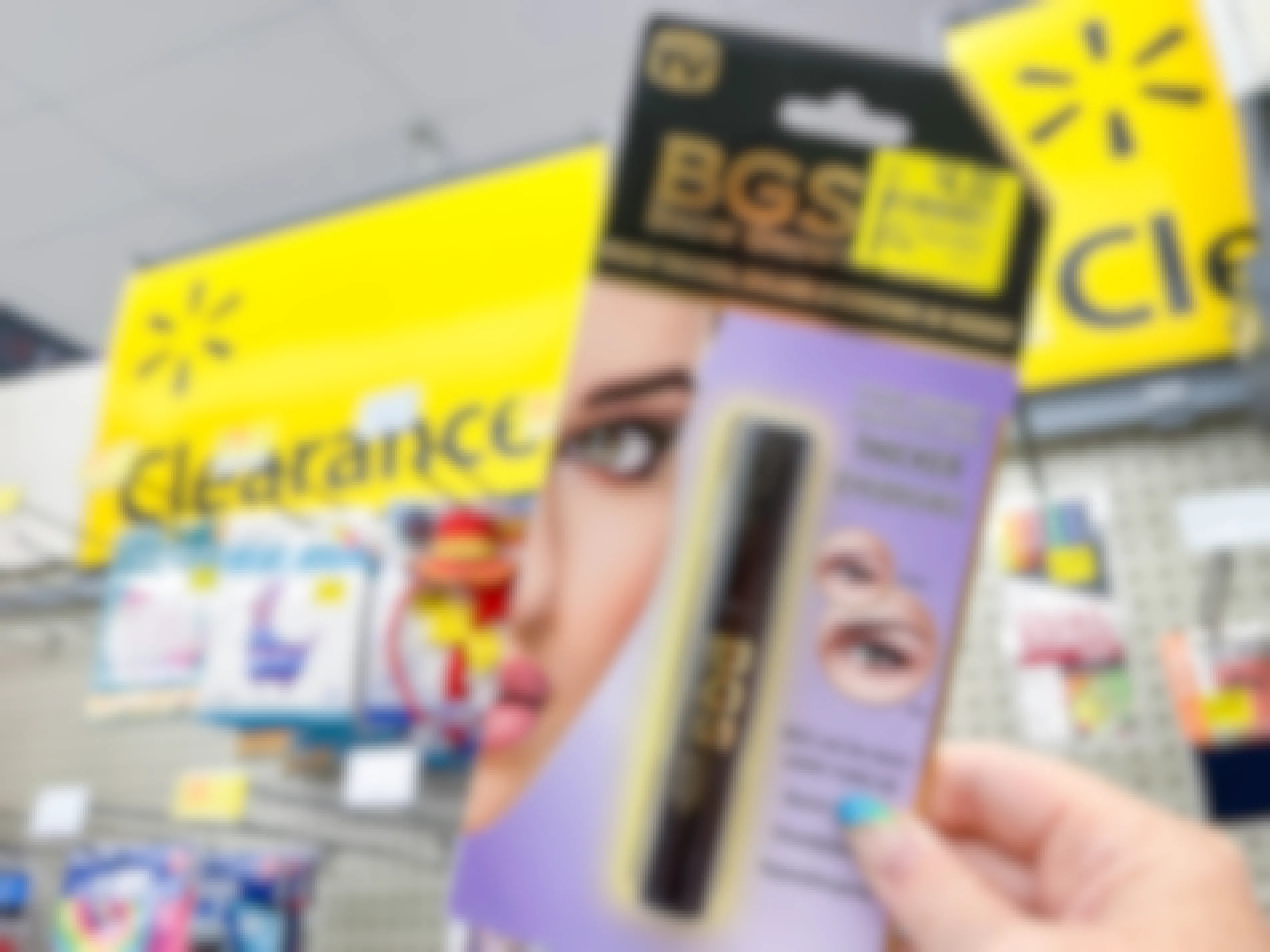 A person holding up clearance makeup product in front of a yellow sign that reads "clearance".