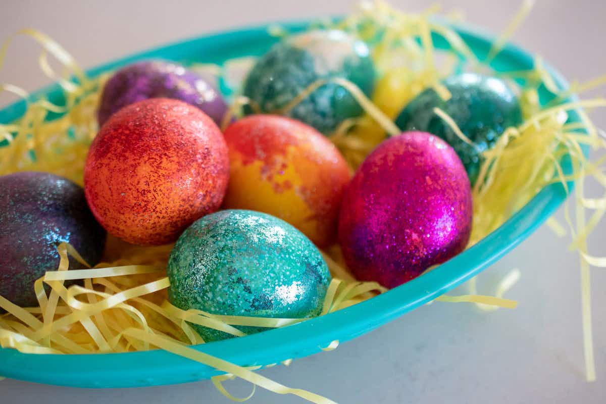 Decorate Easter eggs using a plastic bag, food coloring and glitter.