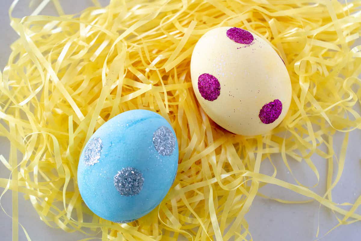 Decorate eggs with glue dots and glitter.
