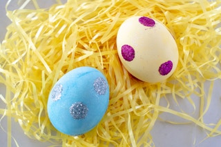 Decorate eggs with glue dots and glitter.