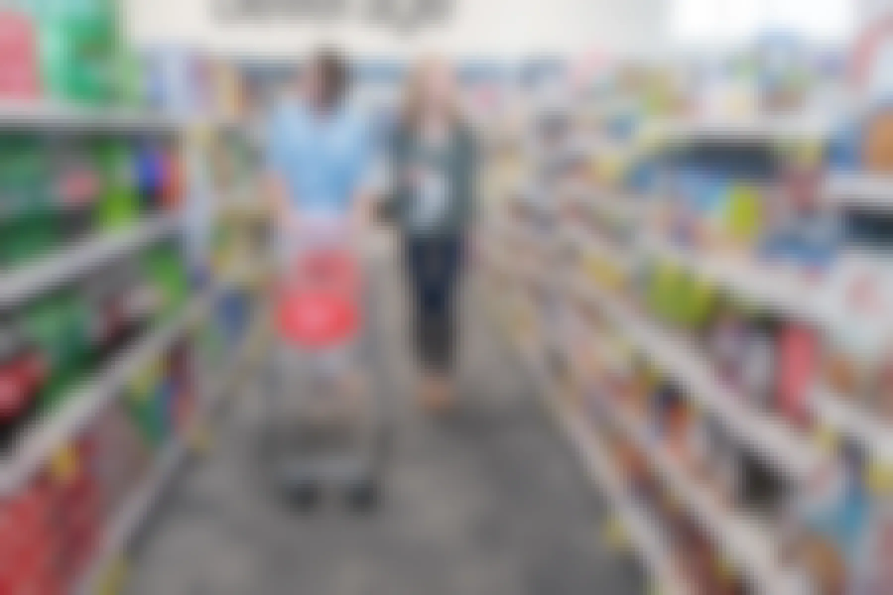 Two women shopping in an aisle at CVS, one of them pushing a CVS shopping cart.