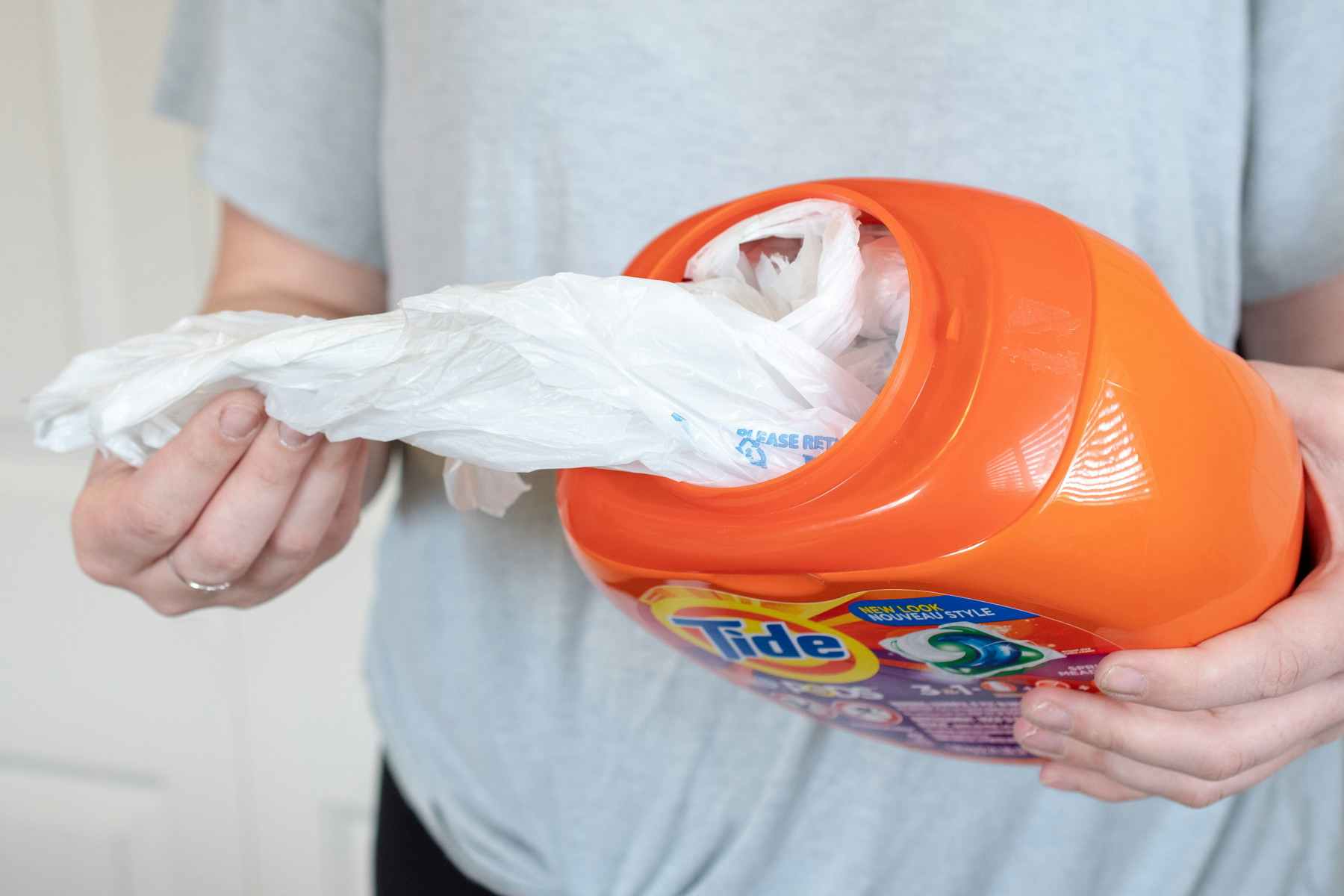 Reuse a laundry detergent bottle to store plastic grocery bags.