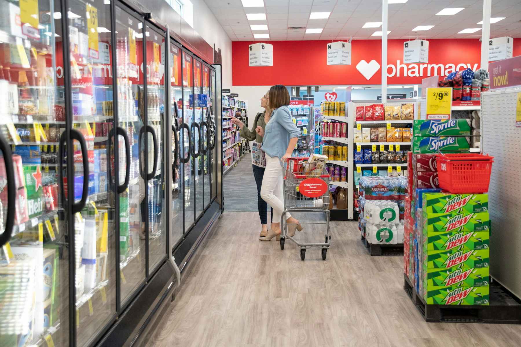 two people in cvs shopping near coolers with pharmacy in the background