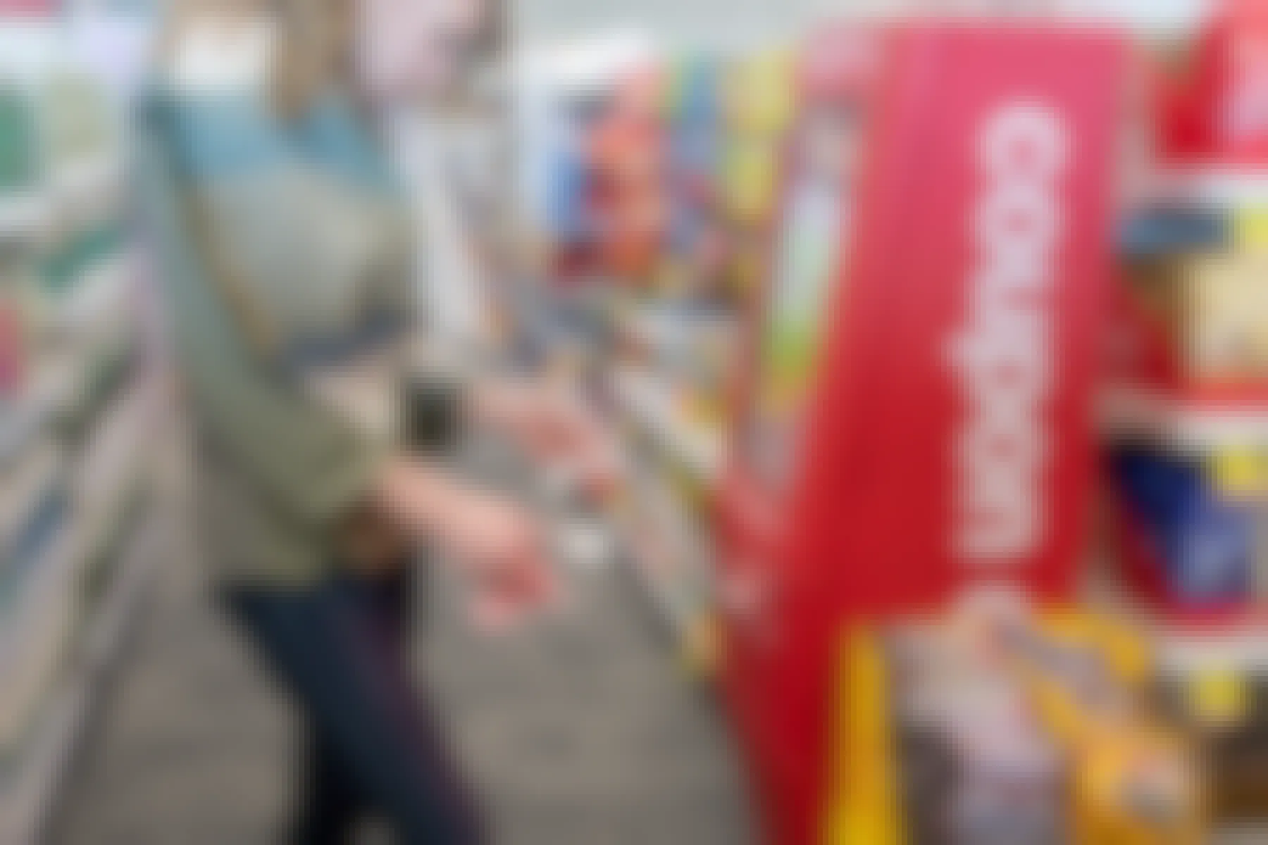 A woman standing and looking down at some coupons in front of a coupon machine at CVS.