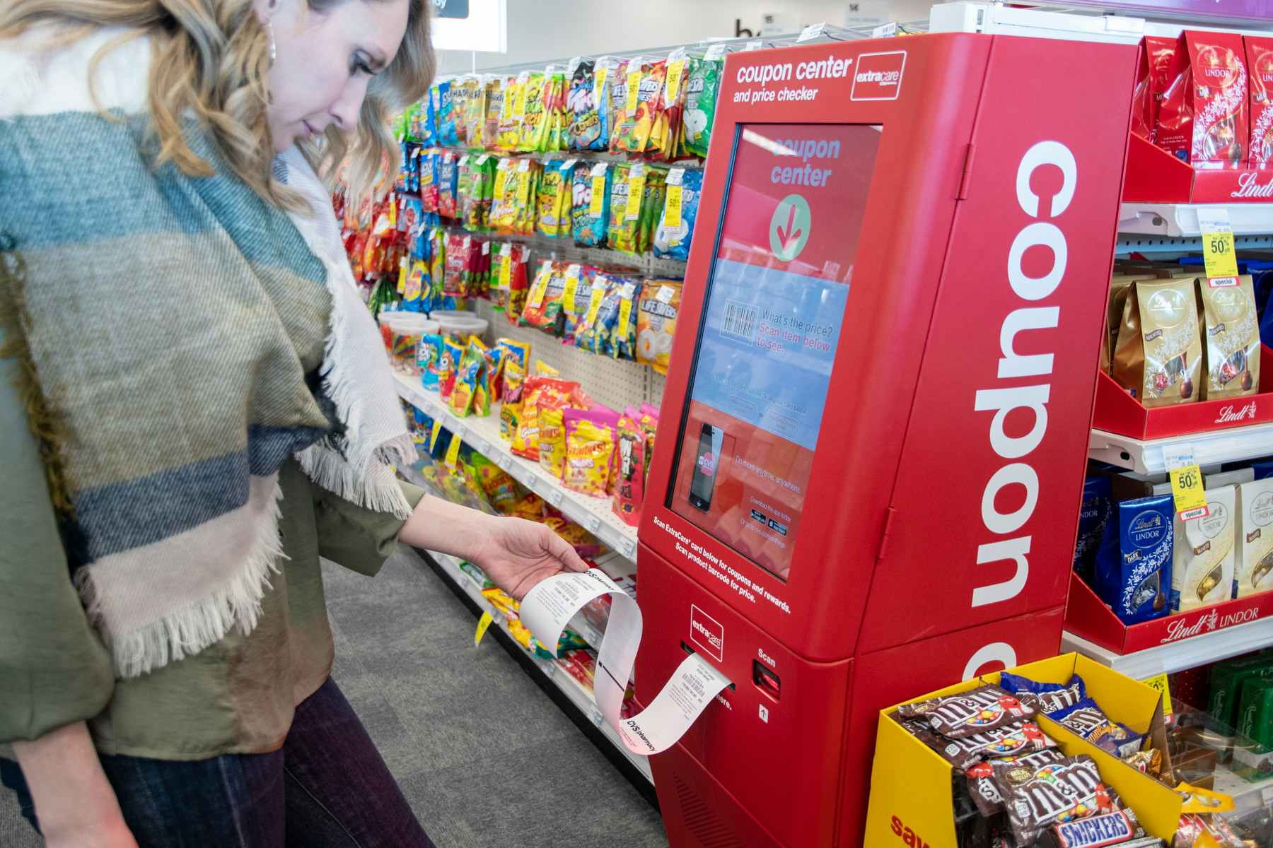woman grabbing coupons from cvs kiosk