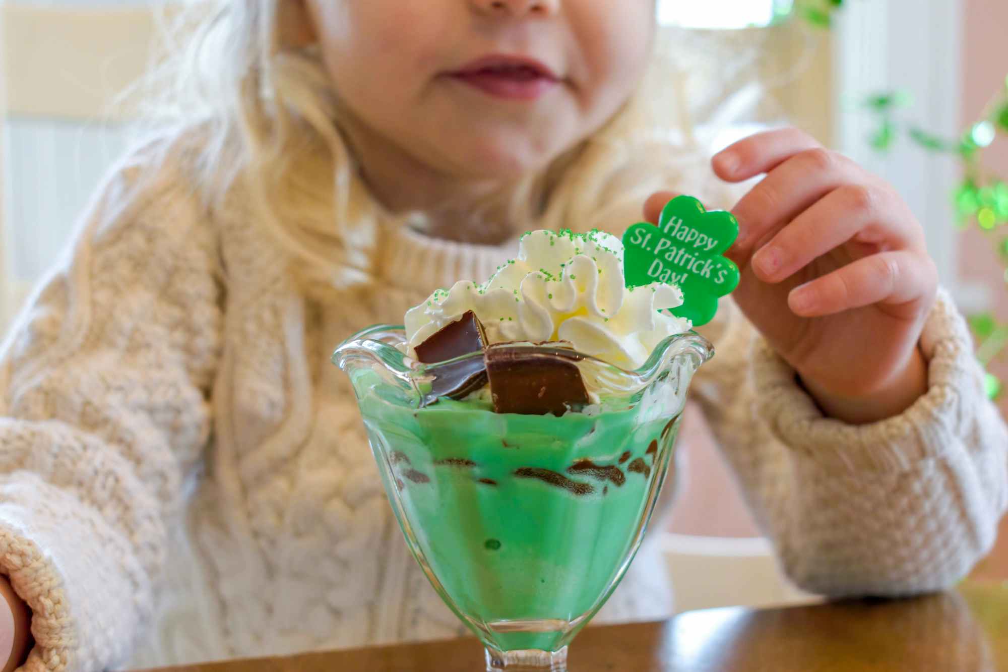 A little girl about to eat a green ice cream sundae