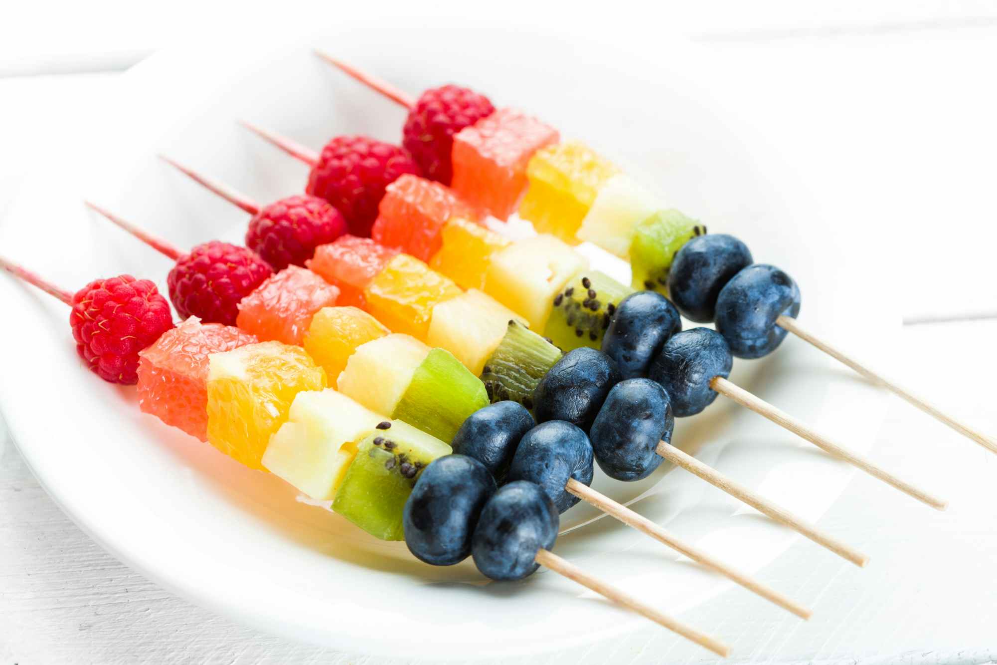 Rainbow colored fruit skewers on a plate 