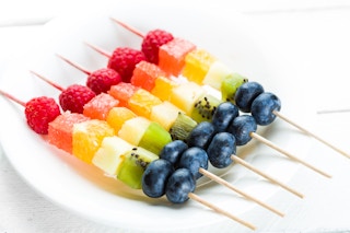 Rainbow colored fruit skewers on a plate 