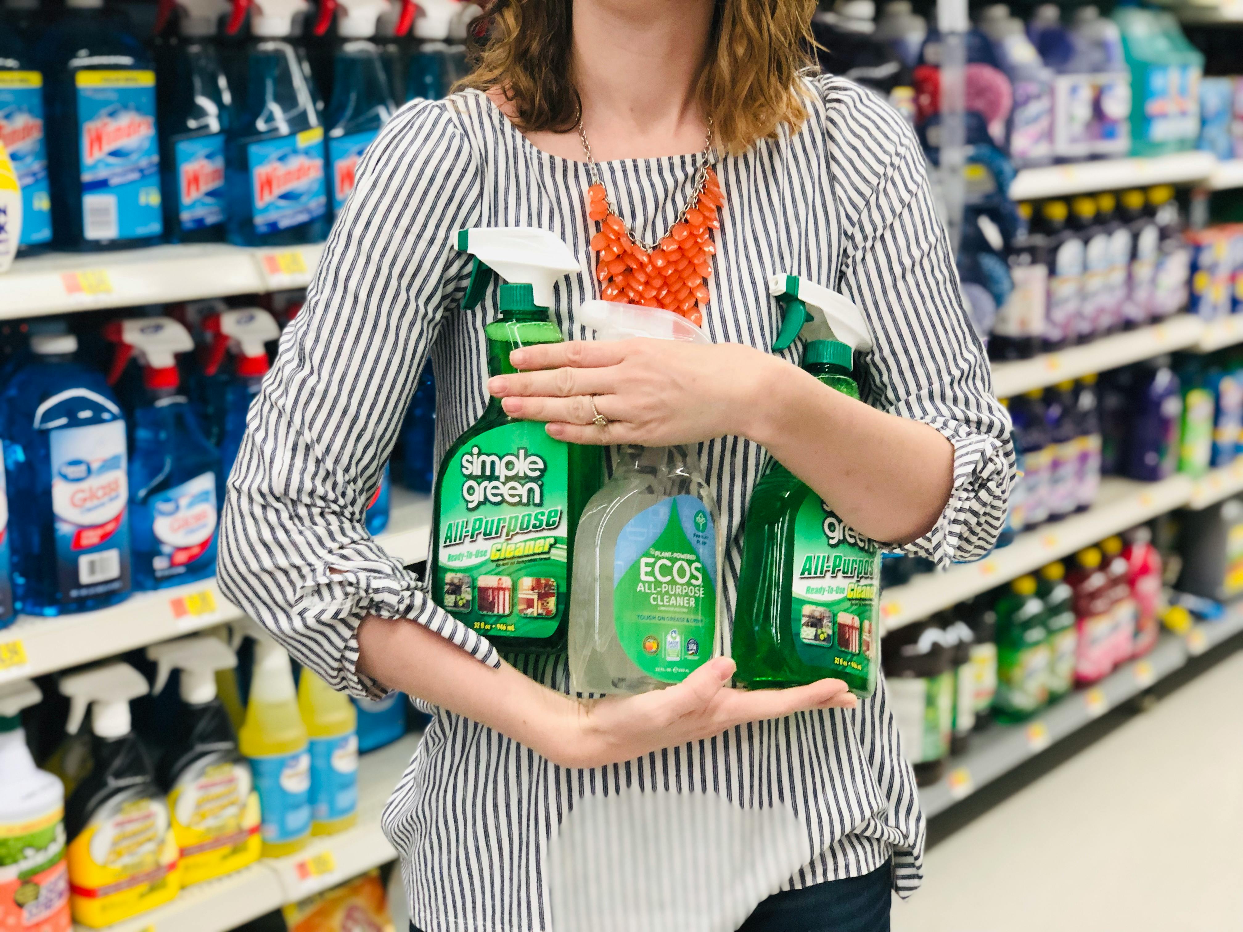A person holding three bottle of simple green cleaners.