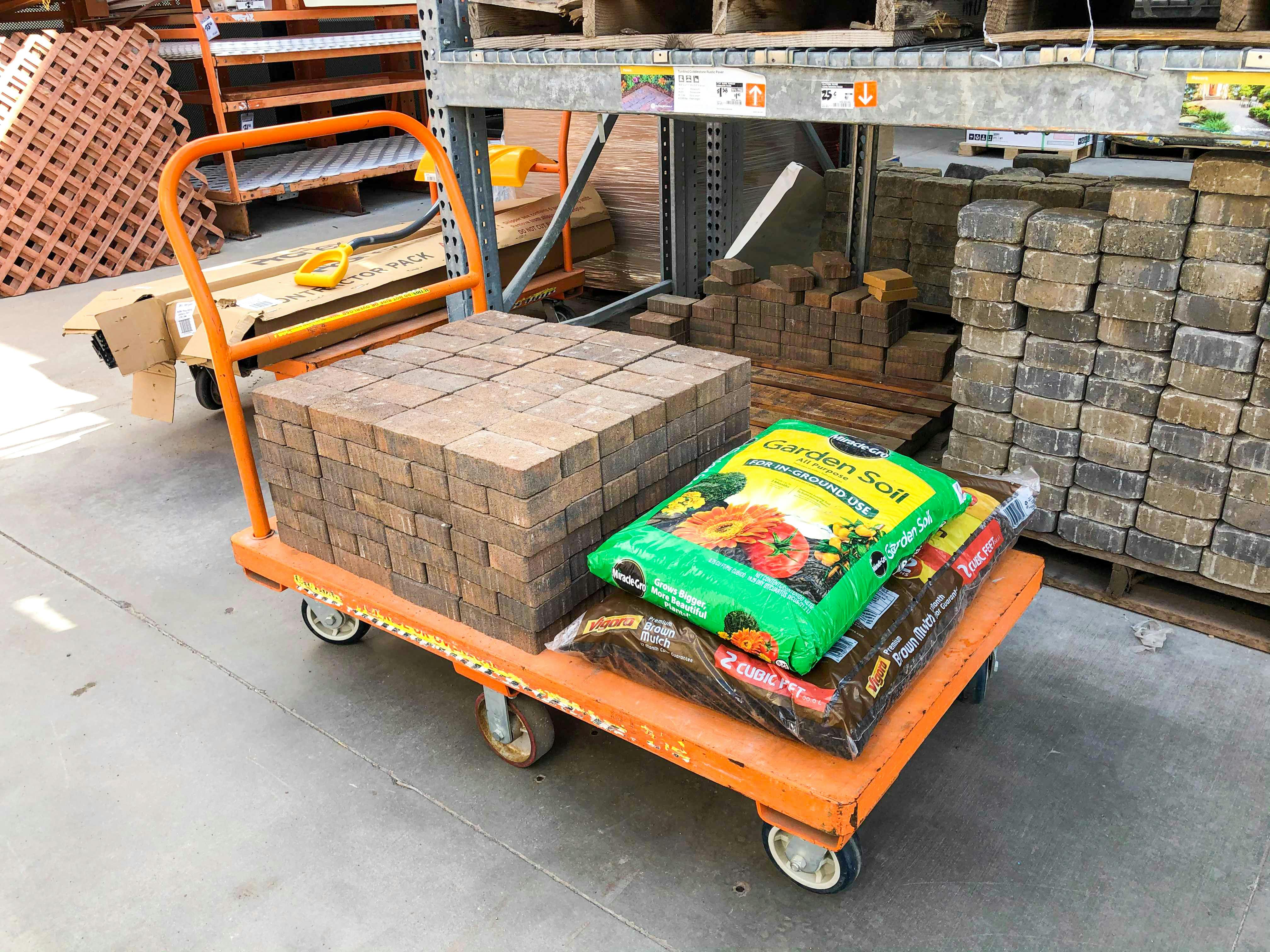 A Home Depot flat cart with pavers, garden soil, and mulch