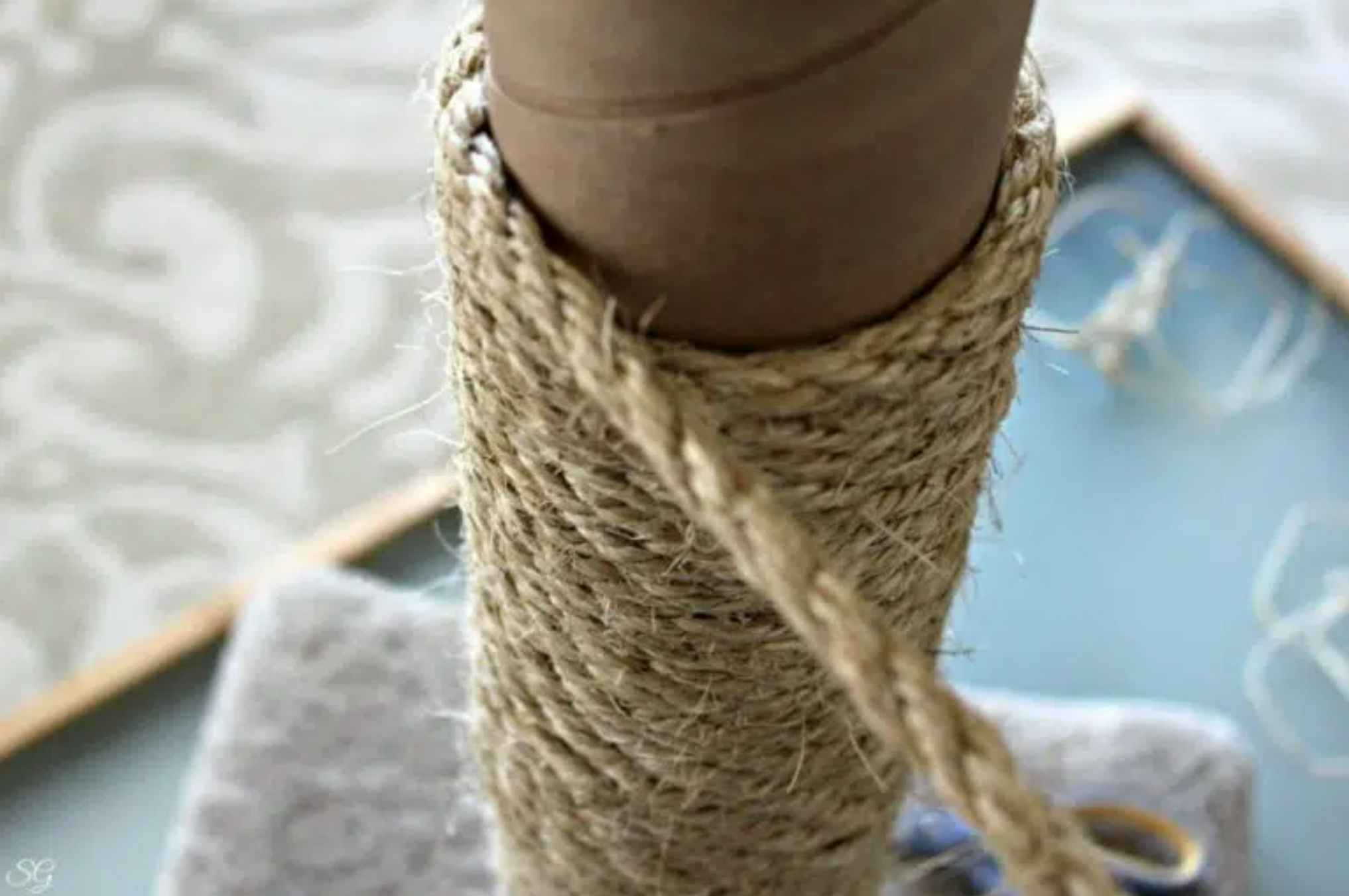 A rope being wound around a bare cat scratching post.