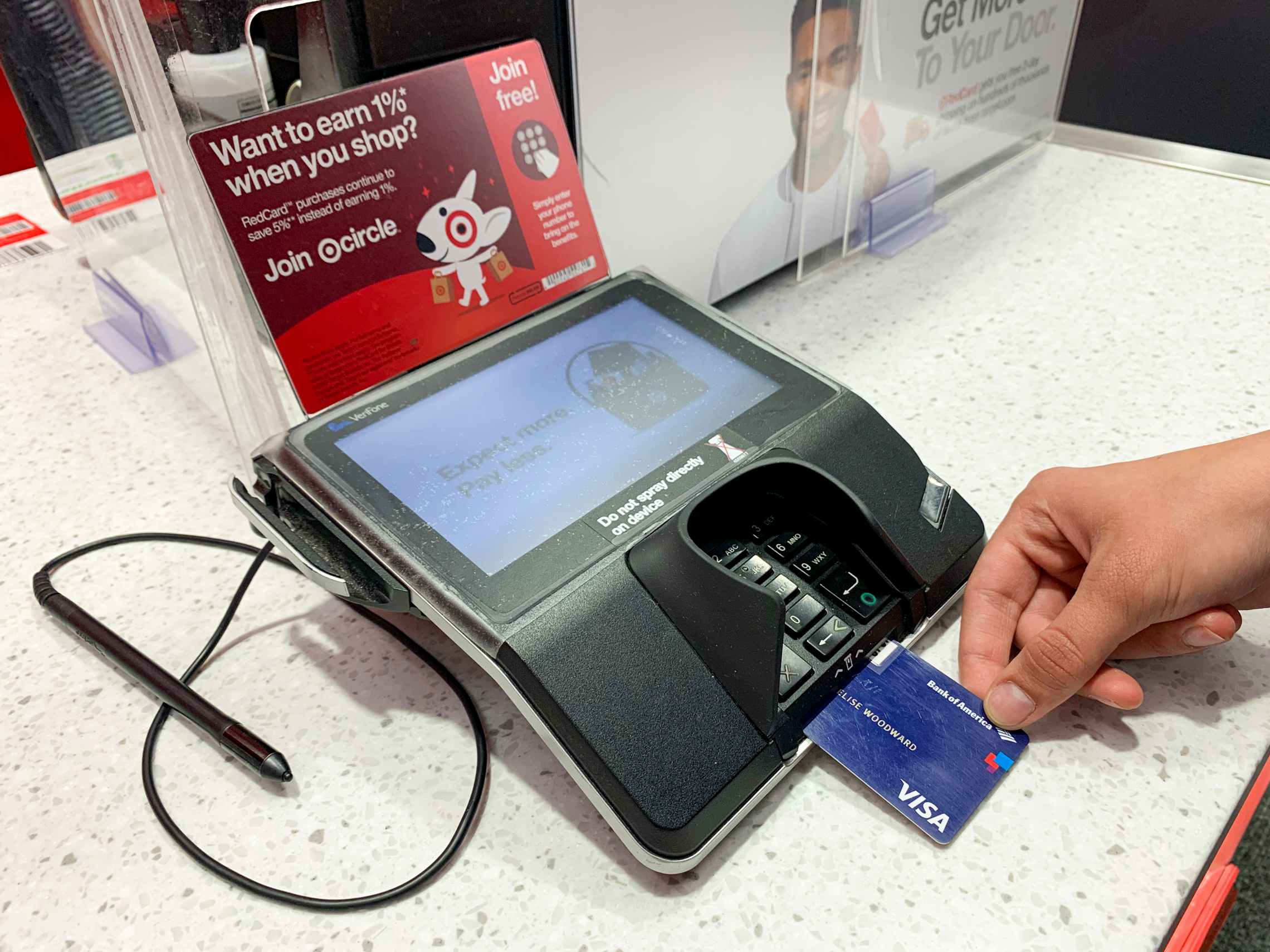 A person inserting their credit card at the credit card machine at a Target counter.