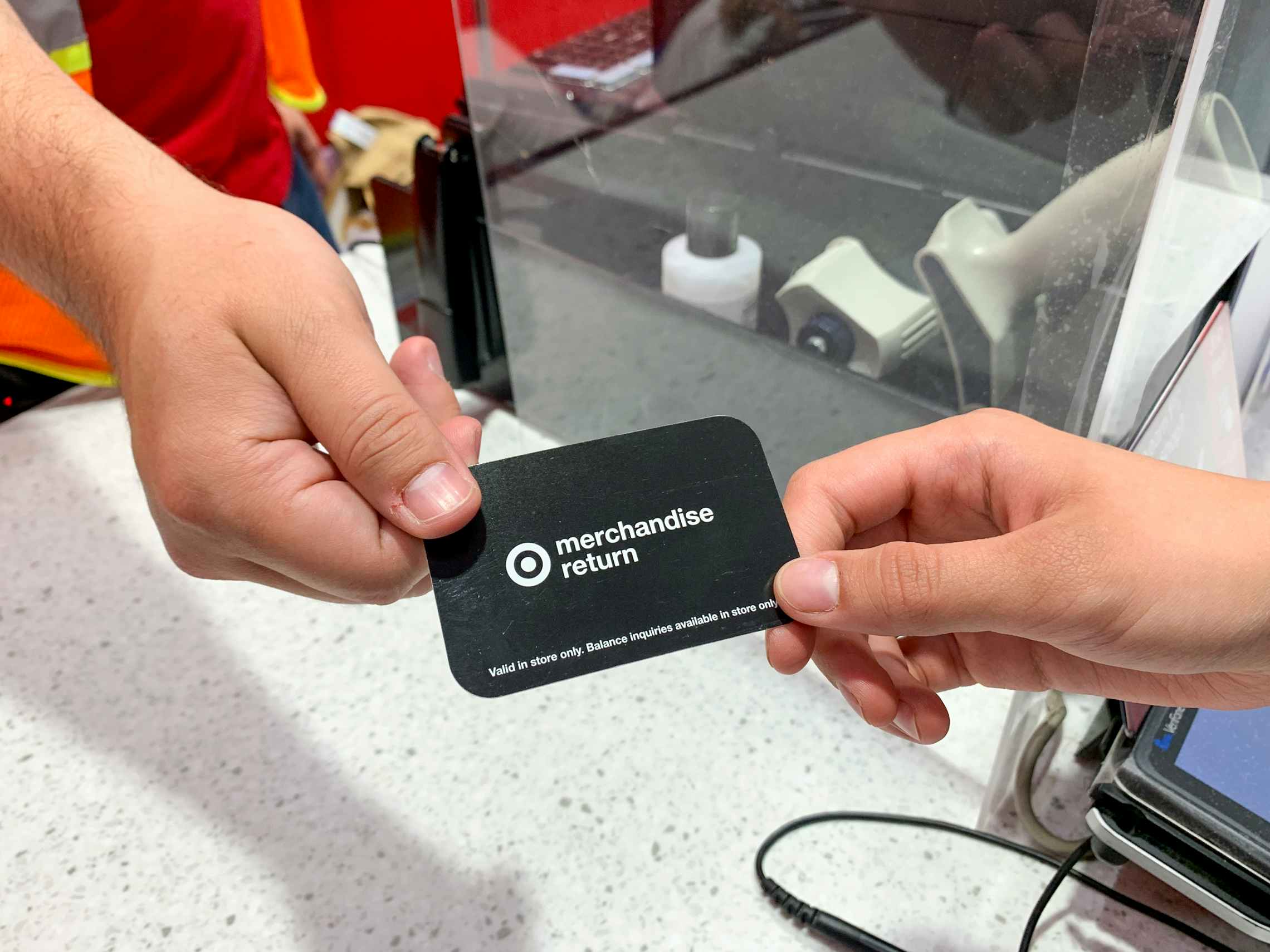 A Target employee handing a merchandise return card to a customer at the checkout counter.