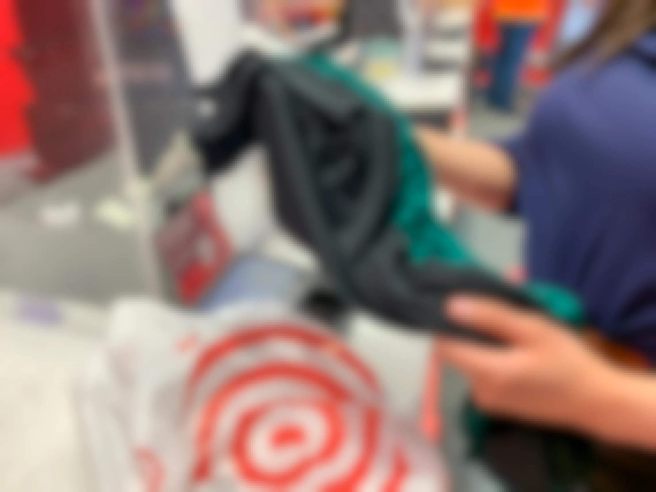 A woman holding two shirts at the Target return counter next to a Target grocery bag.