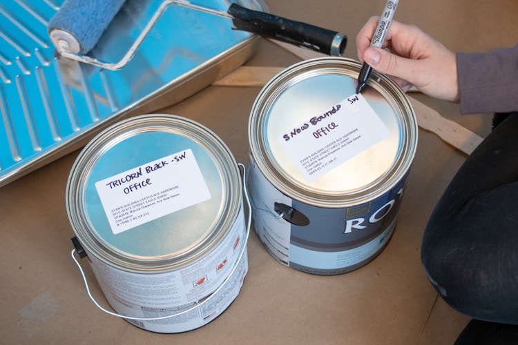 someone writing with sharpie on paint cans