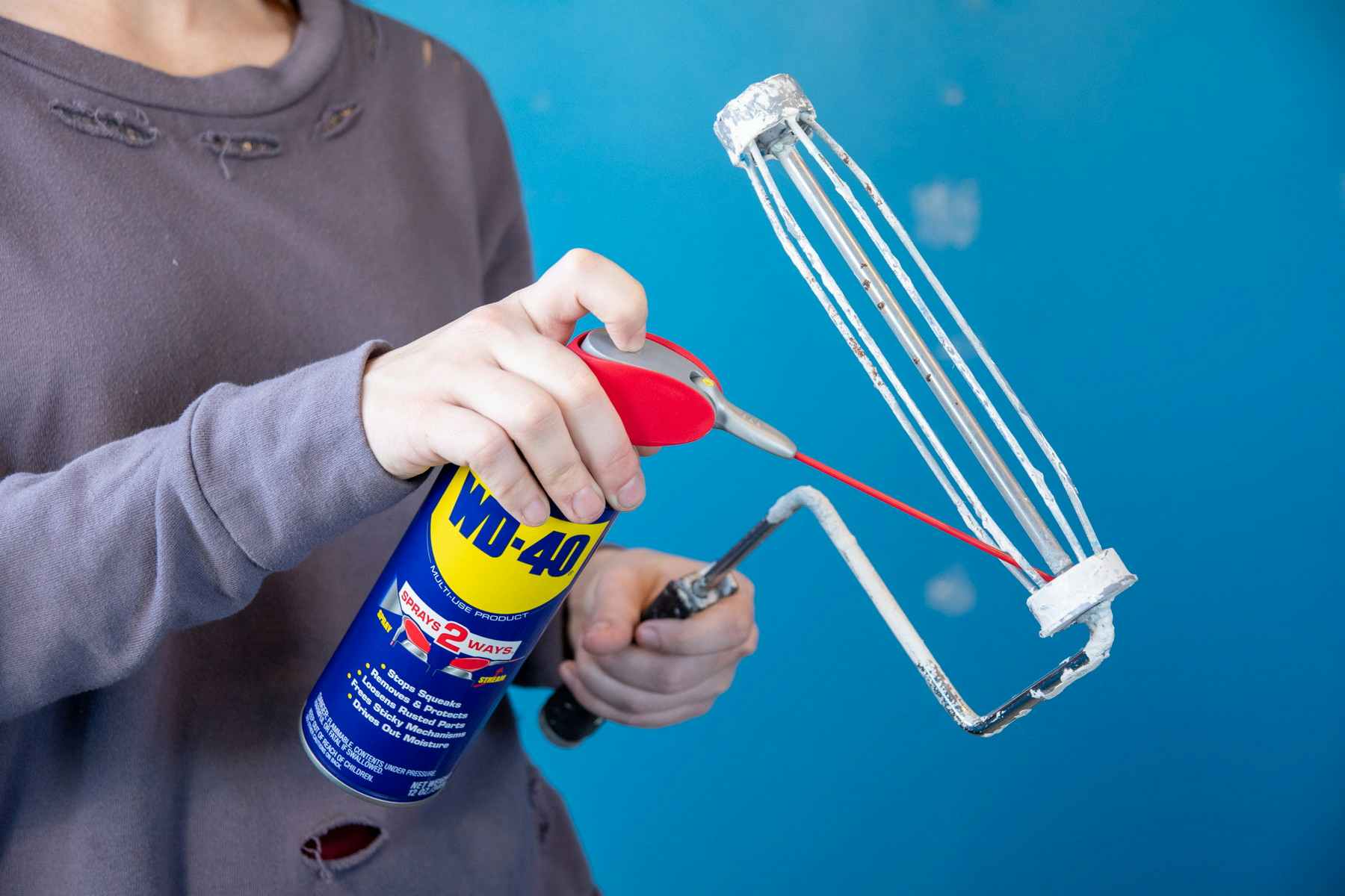 someone spraying WD40 on paint roller