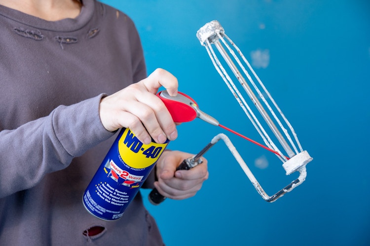 someone spraying WD40 on paint roller