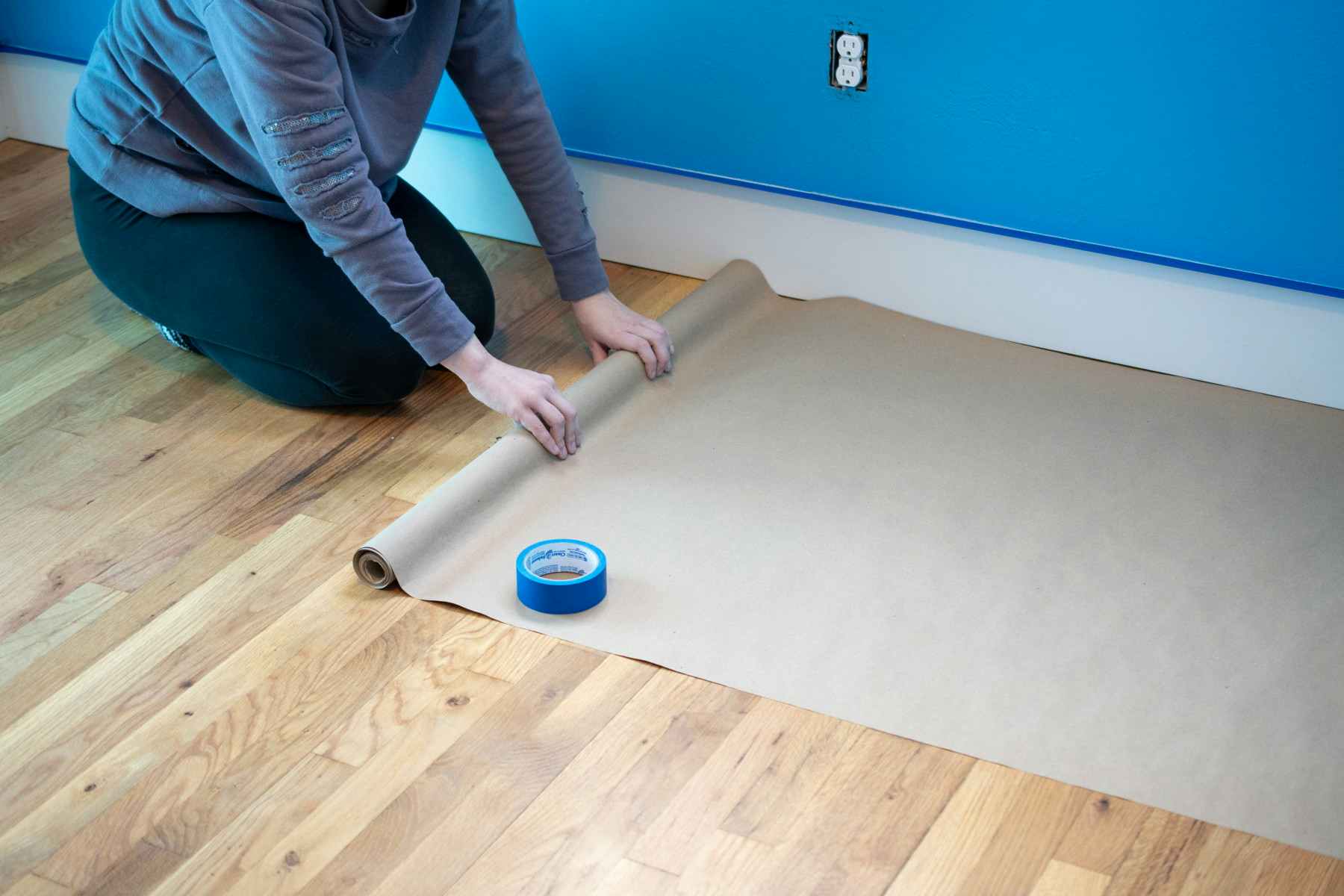 someone unrolling brown paper on floor
