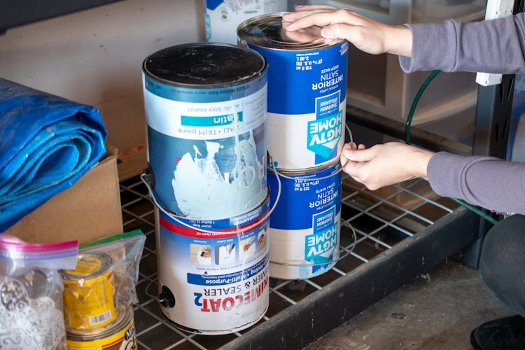 someone putting paint cans on shelf upside down