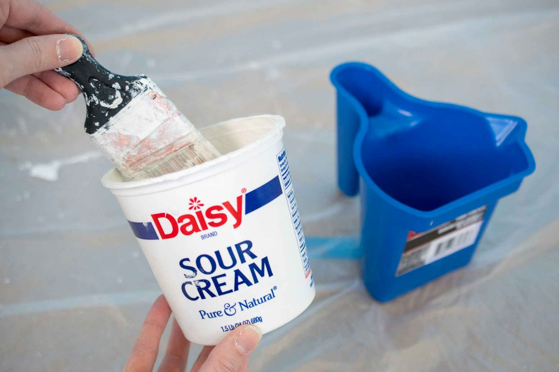 someone putting paintbrush into daisy sour cream container