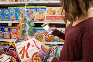 Woman shopping for cereal as she checks her phone