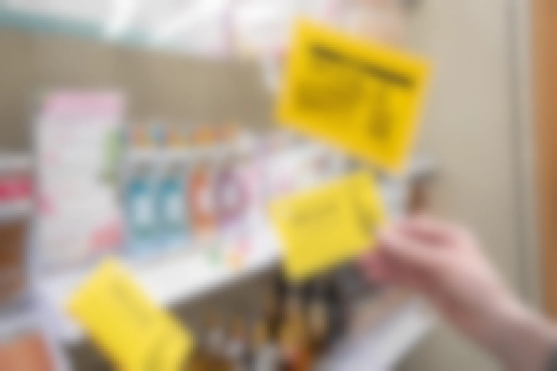 A person's hand holding up a coupon for $3 off next to a shelf with fragrances and more coupons hanging from a hook.