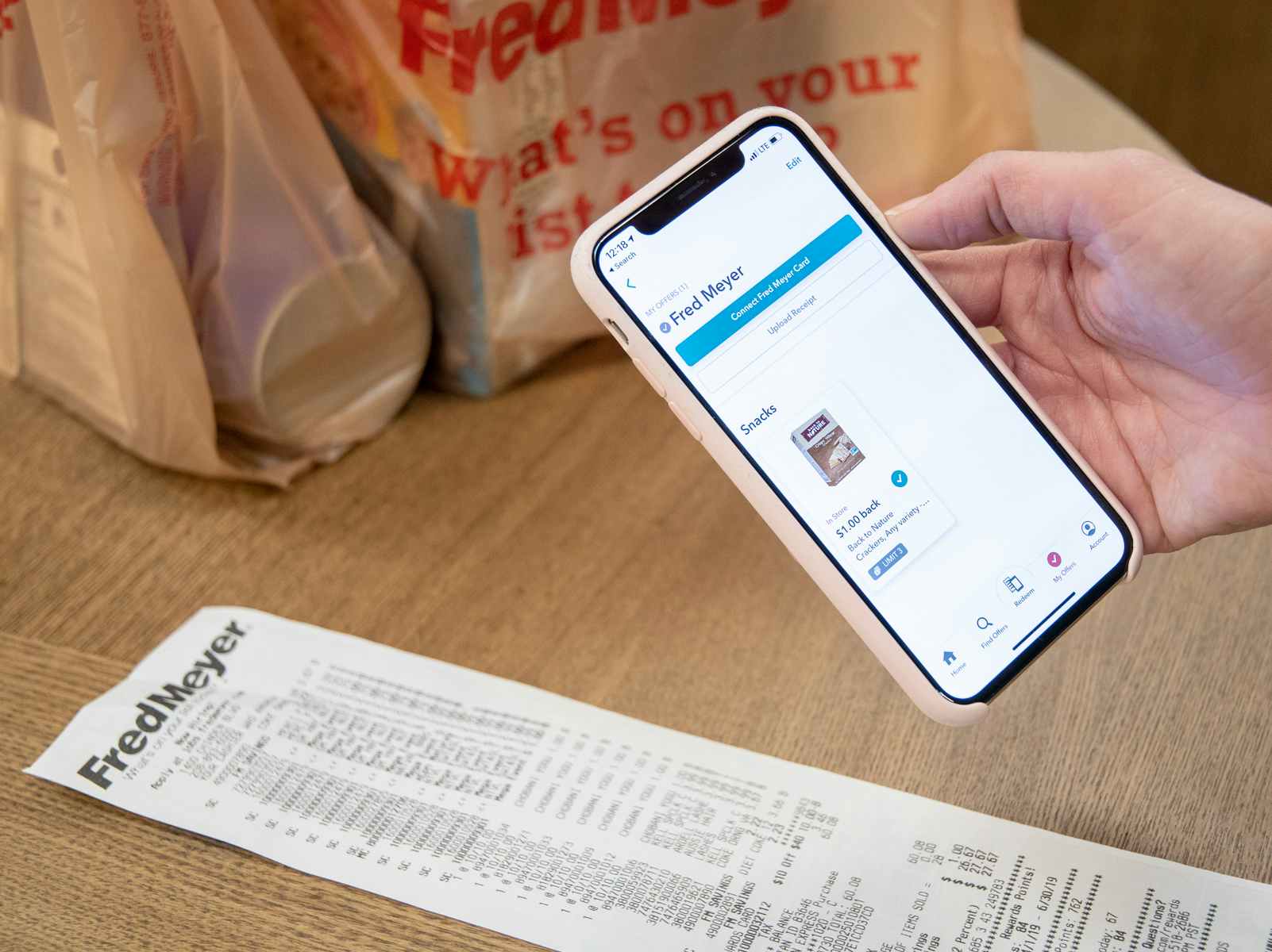 A person holding a smartphone above a receipt to take a photo for the ibotta rebate app.