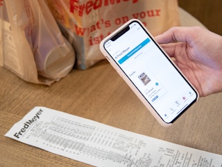 A person holding a smartphone above a receipt to take a photo for the ibotta rebate app.