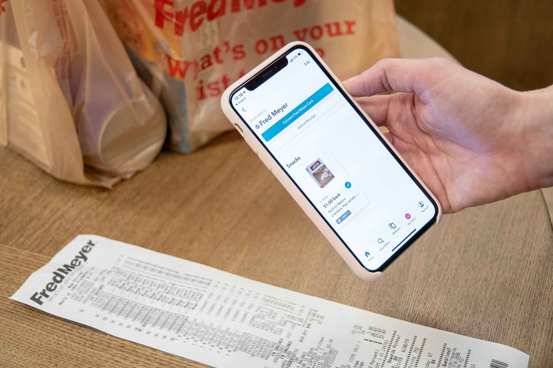 A person holding a smartphone above a receipt to take a photo for the ibotta rebate app.