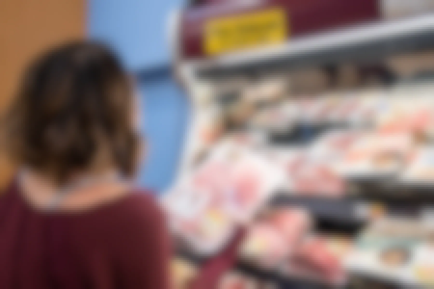 A person looking at a clearance section in a store's meat department.