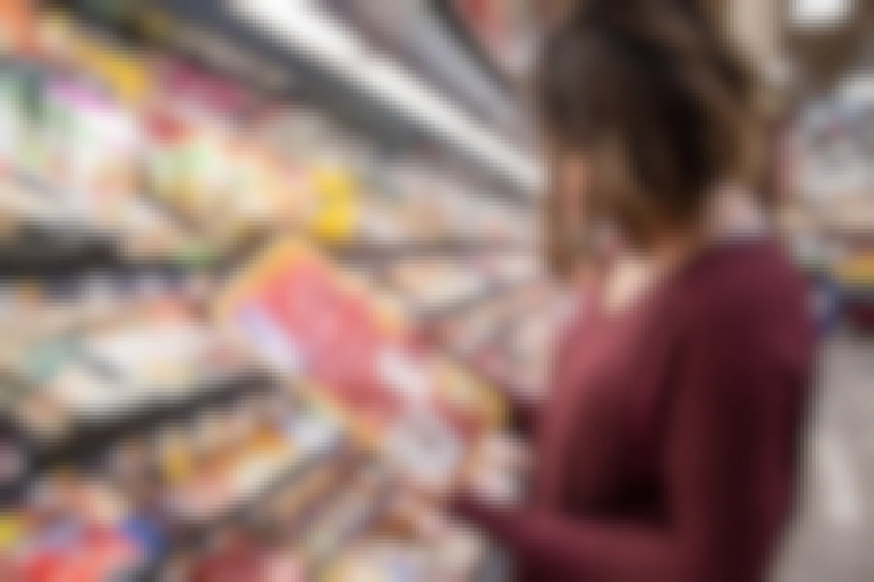 woman looking at meat in a grocery store meat aisle
