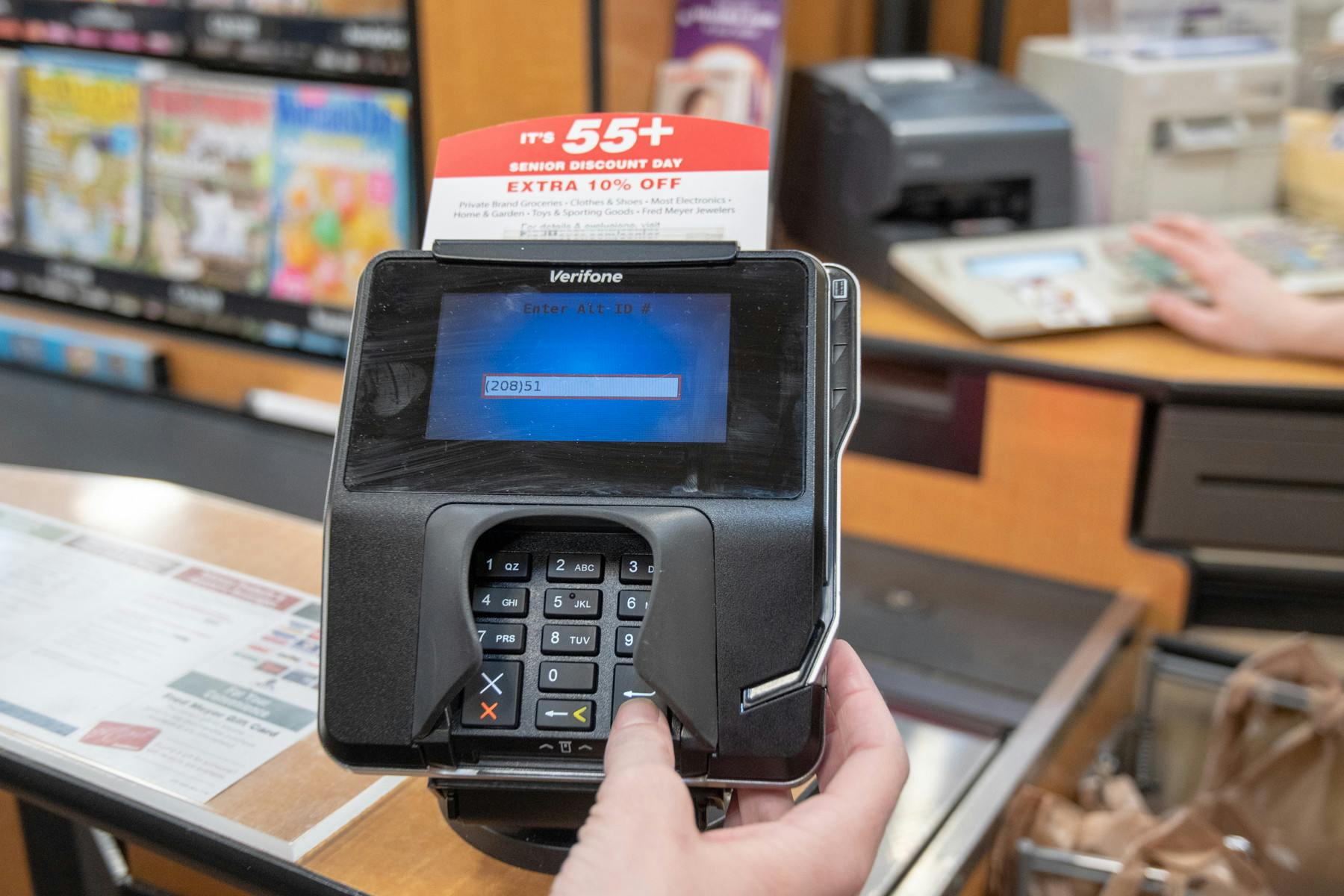 A person inputting card information into a keypad at a store register.