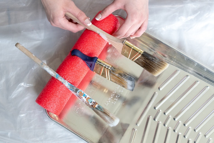 someone putting paintbrushes into slots on pool noodle