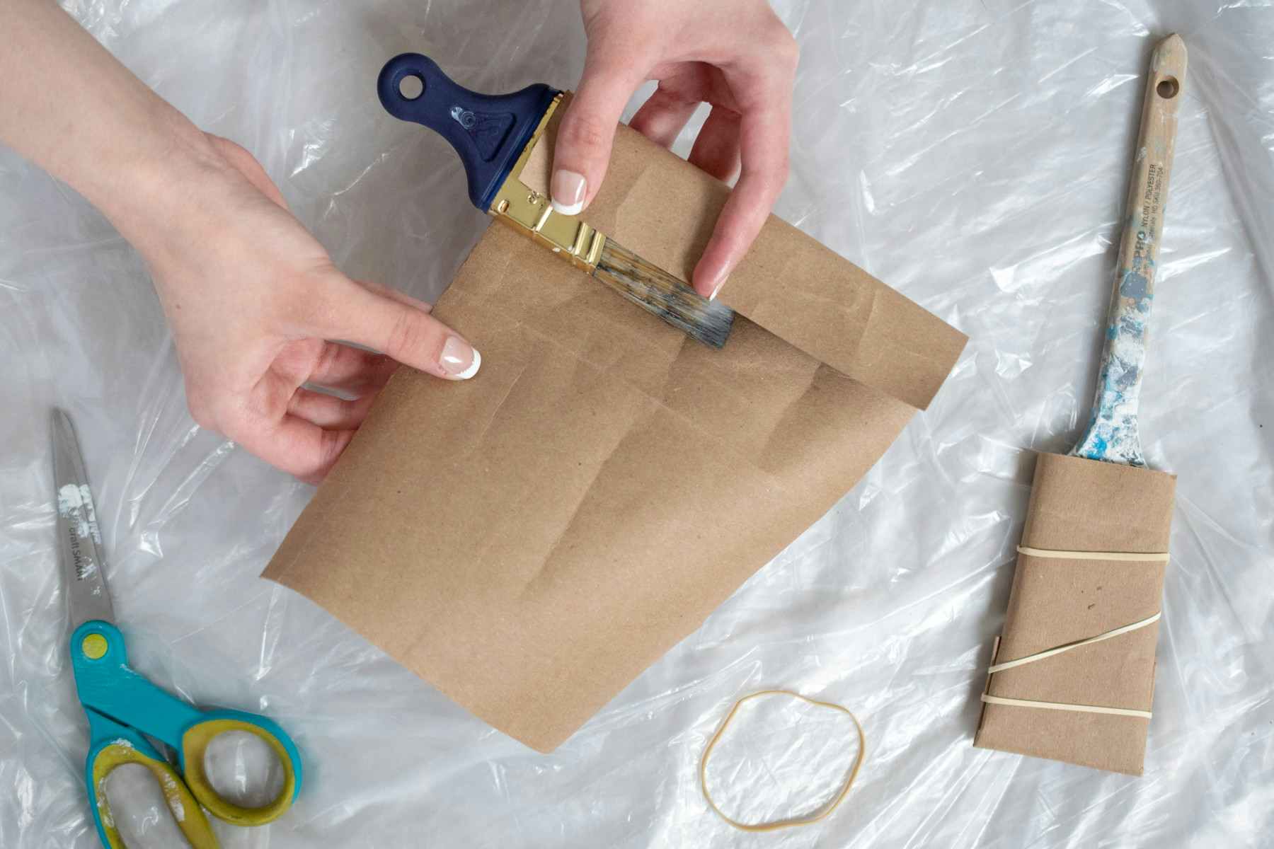 someone wrapping brown paper on paint brush