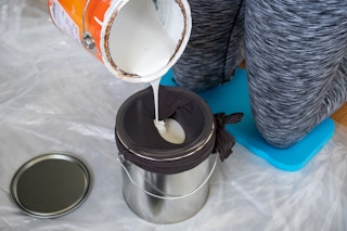 someone pouring paint into bucket with stocking on it