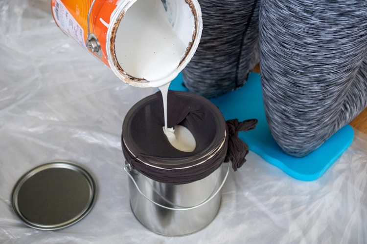 someone pouring paint into bucket with stocking on it