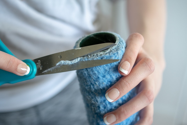 someone cutting edges off paint roller