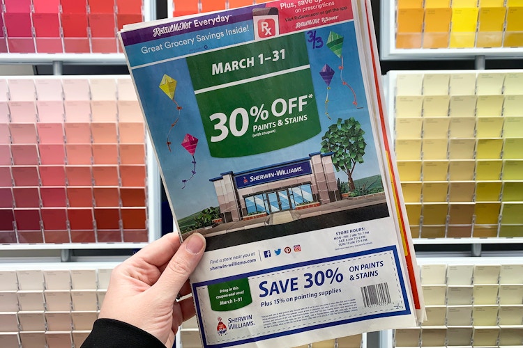someone holding sherwin williams coupon in front of paint