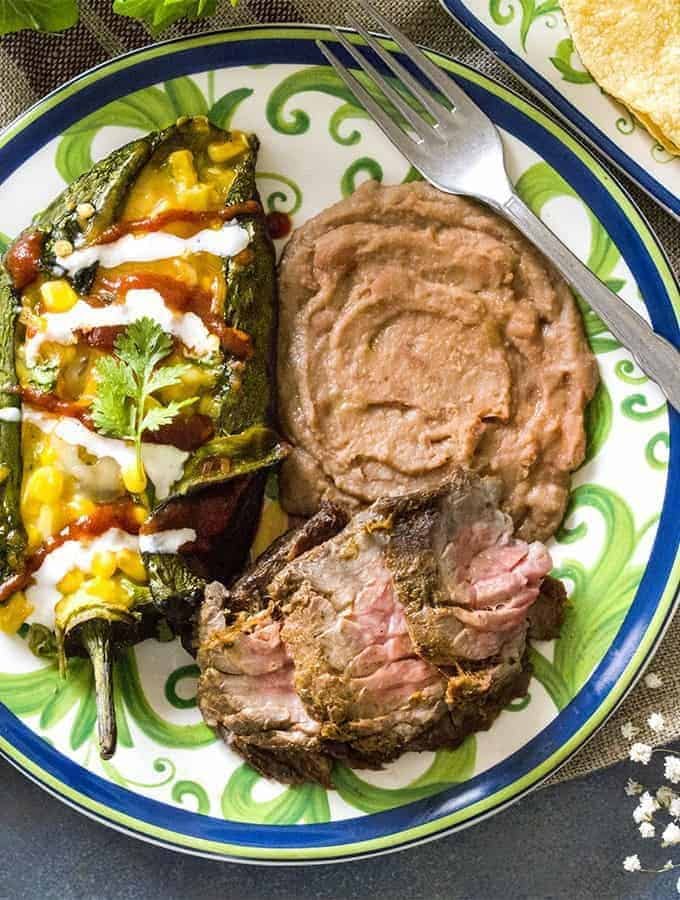 Carne asada on a plate with stuffed pepper and refried beans